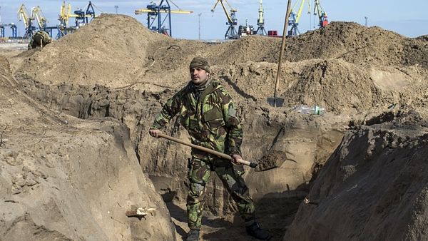 Ukrajinský voják hloubí zákopy na mořském pobřeží u Mariupolu